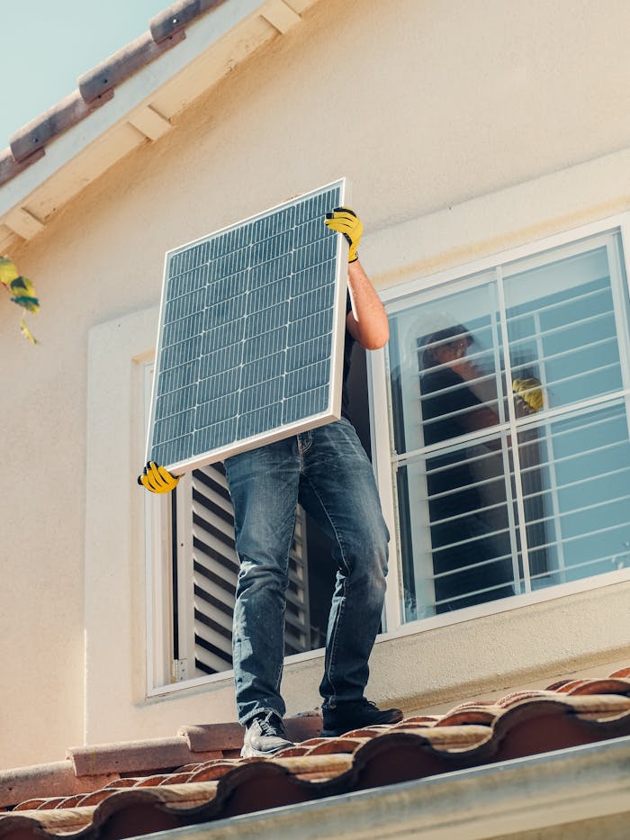 Services-01 Technician carrying a solar panel on a rooftop for installation, promoting renewable energy.