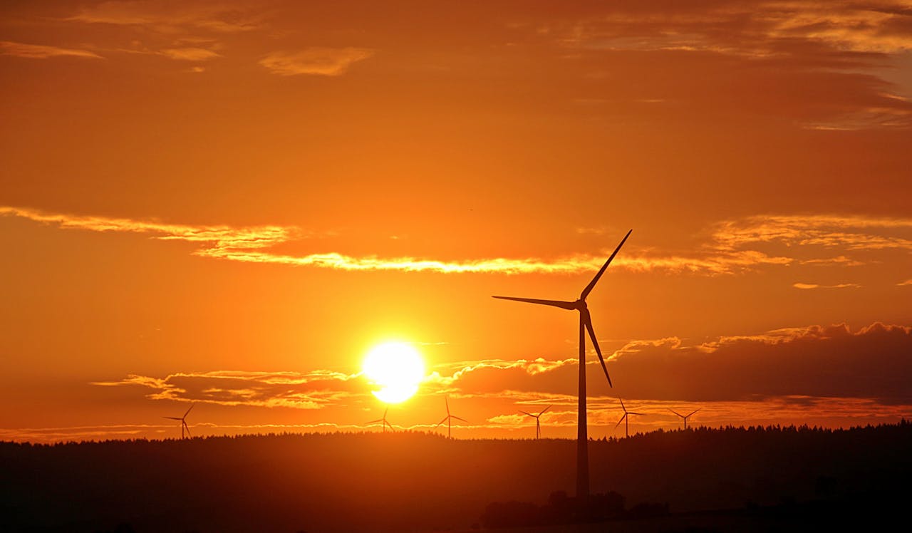 creative-03 Stunning sunset with silhouetted wind turbines, highlighting renewable energy in a serene landscape.