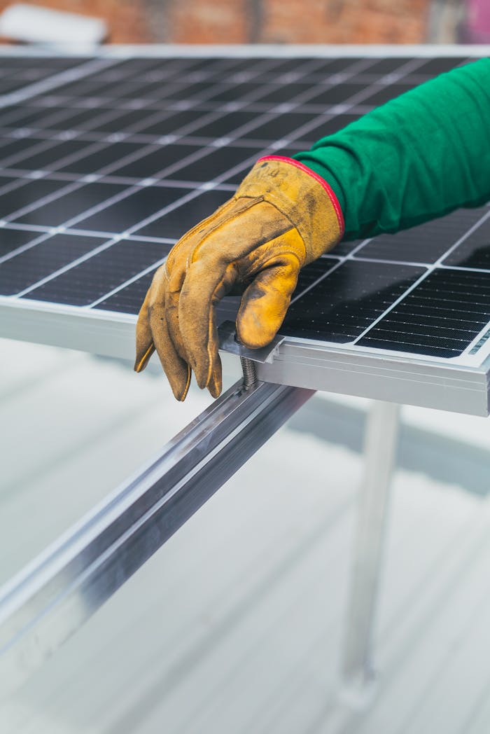 Services-02 Close-up of a workers hand in protective glove installing a solar panel.